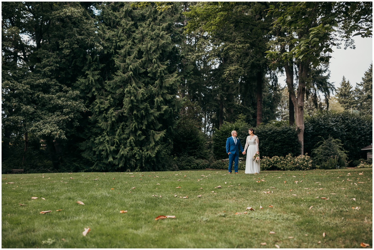 bride and groom standing under trees