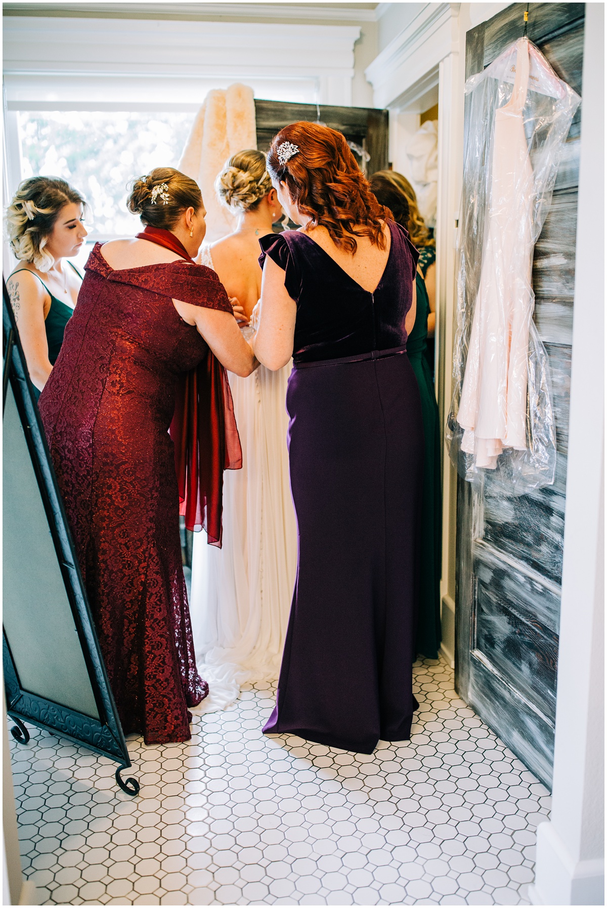 bride getting zipped up by mother and mother in law