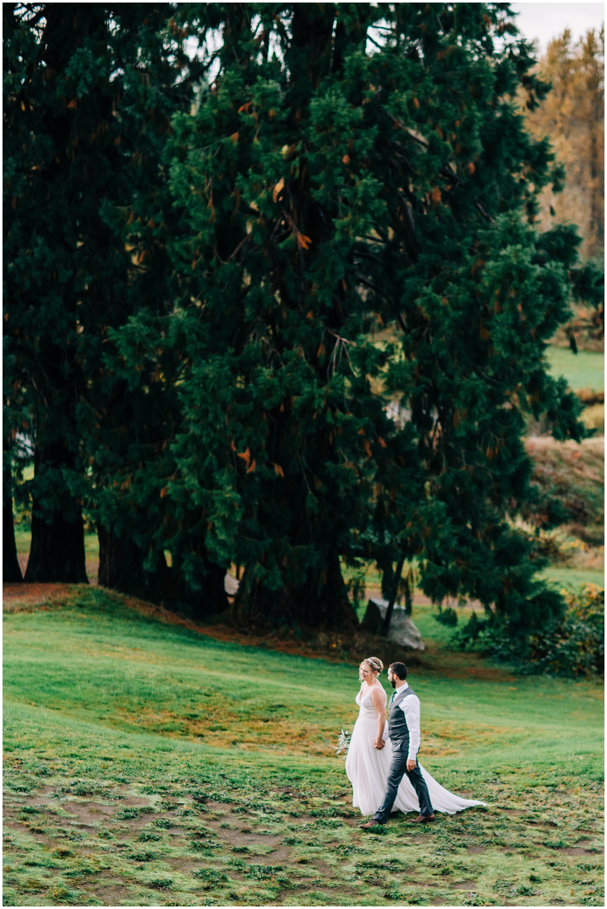 bride and groom walk by trees