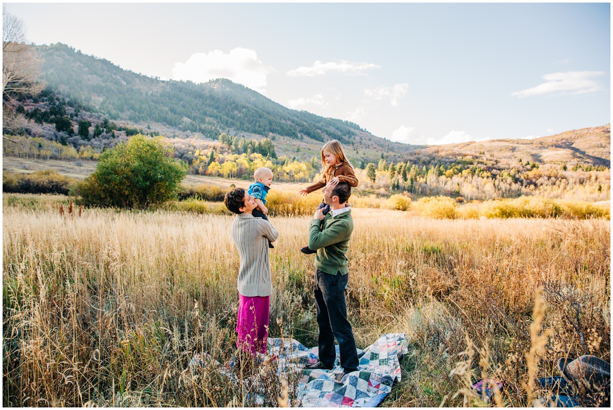 mom and dad standing by a blanket in the field