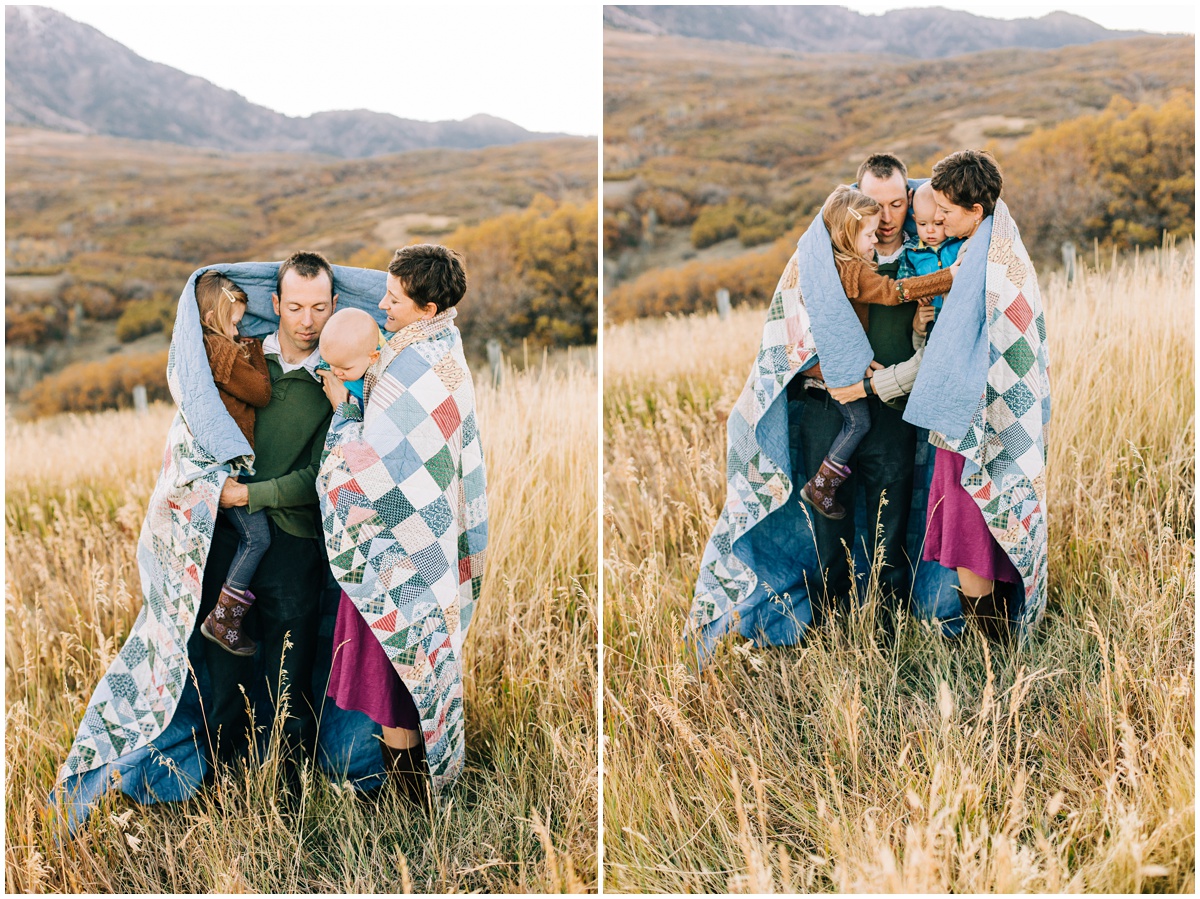 family wrapped in a quilt in a field 