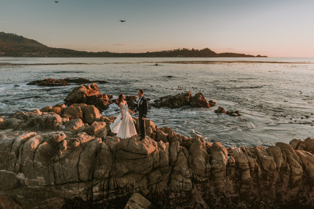 couple standing on rocks in the ocean