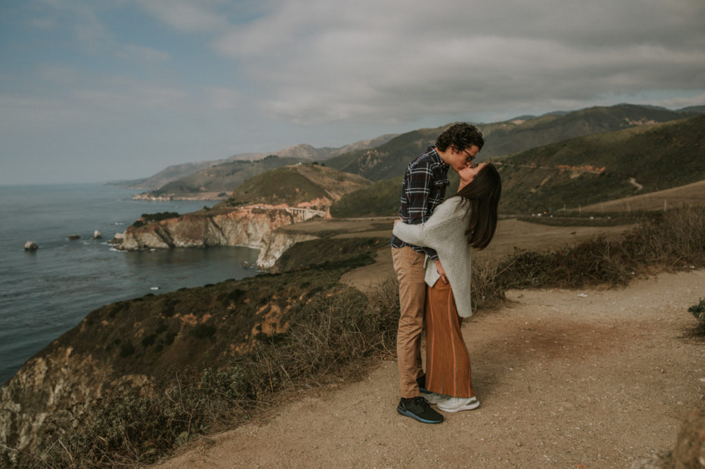 couple kissing by bridge overlook