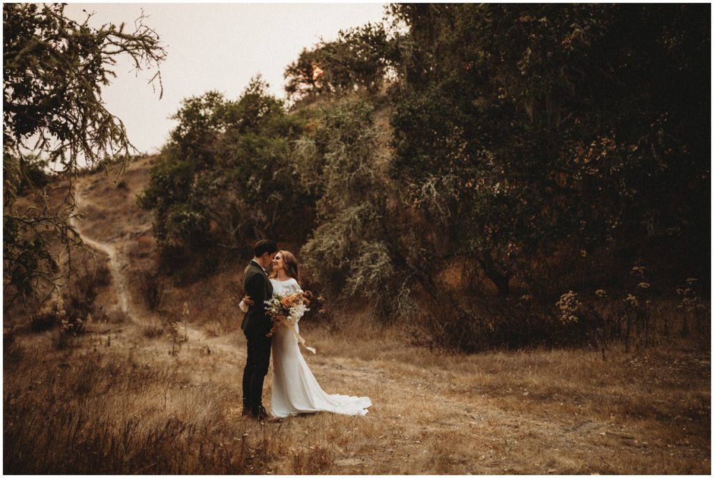 bride and groom standing by trail