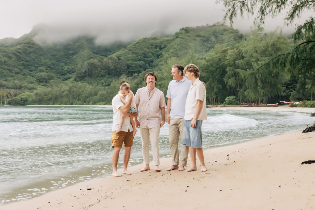 men standing on the O'ahu beach dressed in cream, brown, blue, and rose