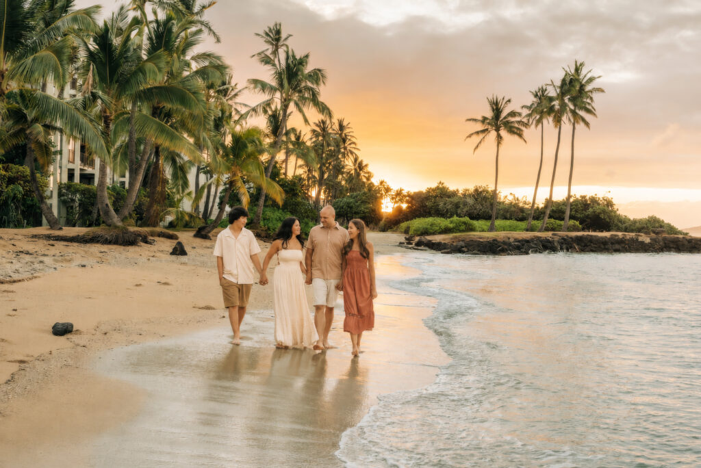 Family walking on Hawaii beach dressed in warm sunset colors